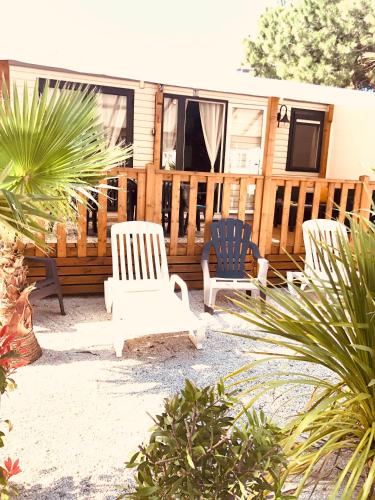 une terrasse avec trois chaises et une maison dans l'établissement Mobil home, au Grau-dʼAgde