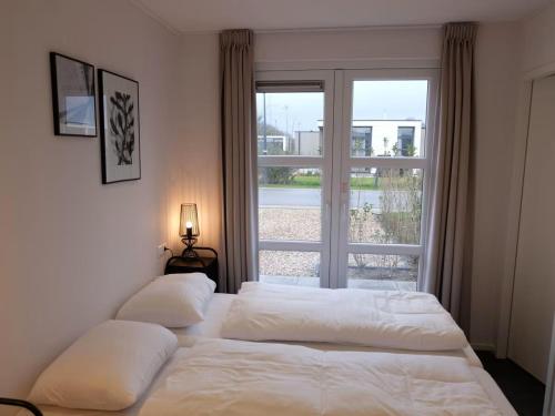 two beds in a bedroom with a large window at Marina Strandbad Chalet SunnyTides Haus Nr 36 in Olburgen