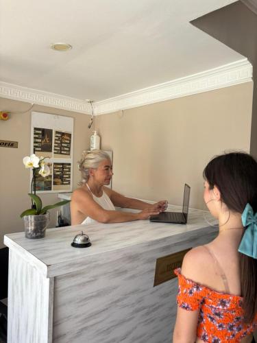 a man sitting at a counter with a laptop at MOY Beldibi Hotel in Antalya
