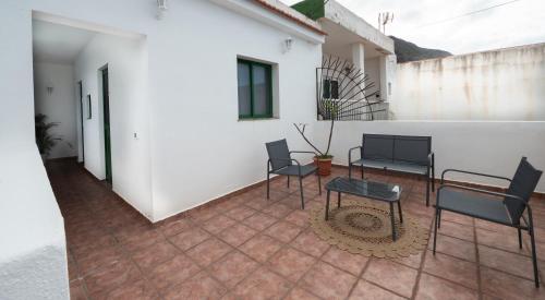 a patio with chairs and a table and a white wall at Casa Abuela Juana in Sabinosa