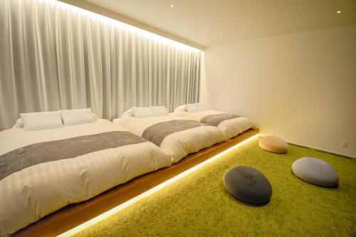 a bedroom with two beds and two ottomans at Yoichi Nap in Yoichi