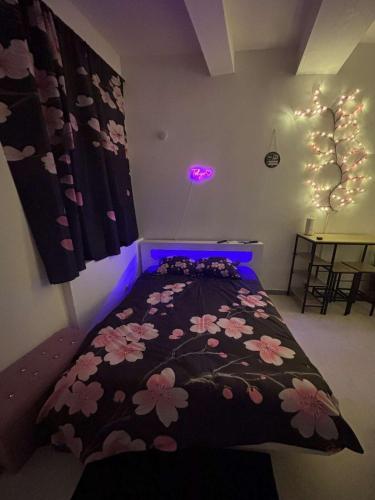 une chambre avec un lit avec une couverture noire avec des fleurs roses dans l'établissement Tokyo love, à Montpellier