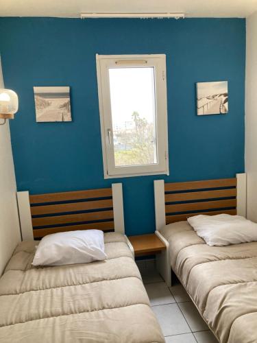 - 2 lits dans une chambre avec un mur bleu dans l'établissement 2 pièces terrasse vue mer Le cap d'Agde, au Cap d'Agde