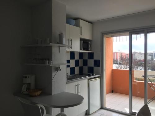 une cuisine avec une table et une vue sur un balcon dans l'établissement 2 pièces terrasse vue mer Le cap d'Agde, au Cap d'Agde