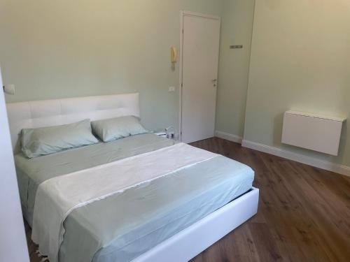 a bedroom with a white bed and a wooden floor at Monolocale Salvia Self check in in Pavia