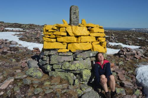 a woman is sitting in front of a stone monument at 16 - Fulufjellets nasjonalparker - snø - alpint - langrenn - snøscooter in Ljørdal