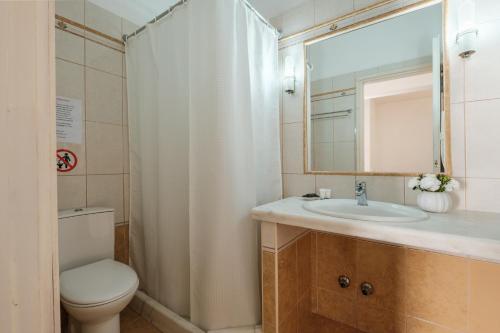 a bathroom with a toilet and a sink and a mirror at Kalamionas Studios & Apartments in Kassiopi