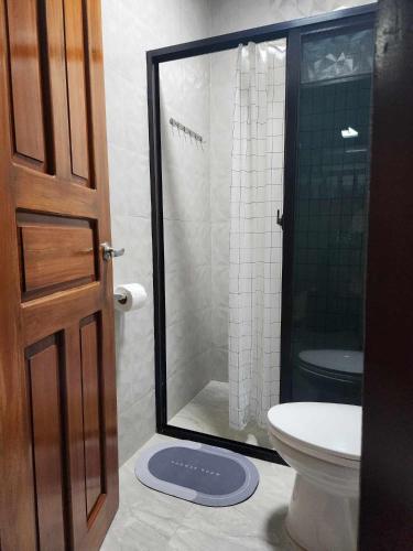 a bathroom with a toilet and a glass shower at Goldland Caelestis Guest House in Bacolod
