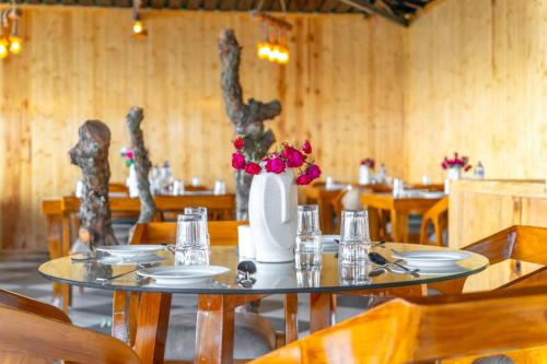 a dining room with a table with a vase of flowers at Ila by Aaryam, Kanatal in Chamba