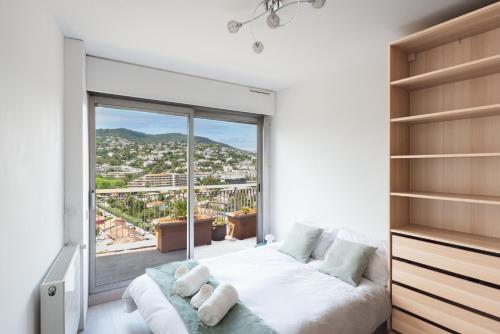 une chambre avec un lit et une grande fenêtre dans l'établissement Le Rooftop - Piscine - Terrasse - Barbecue - Accès plage, à Mandelieu-la-Napoule