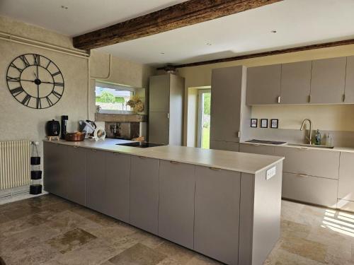 une cuisine avec un grand comptoir et une horloge murale dans l'établissement Le Prieuré, à Belmont