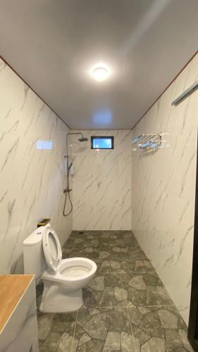 a bathroom with a toilet and a shower in it at Lombok Grace Bungalows in Tetebatu