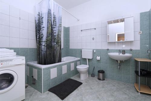 a bathroom with a sink and a toilet and a tub with a plant at Apartments Villa Flamingo in Makarska
