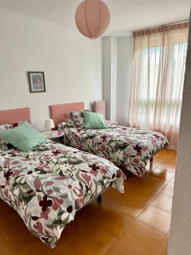 a room with two beds and a table and a window at Apartamento MILA centro in Comillas