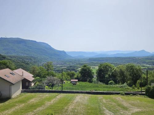 - une vue sur un champ avec une maison et des montagnes dans l'établissement Le Prieuré, à Belmont