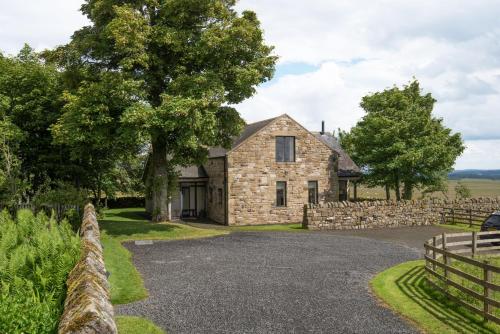 a stone house with a stone fence and a driveway at Vesta View in Hexham