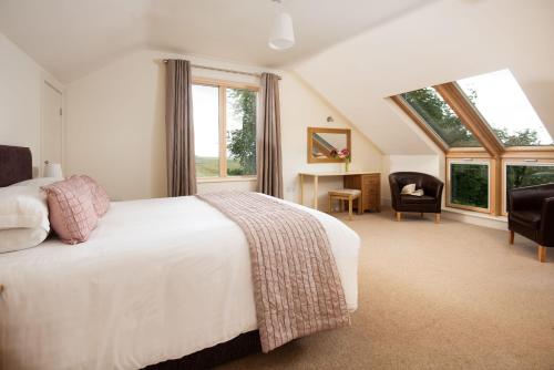 a bedroom with a large white bed and windows at Vesta View & Shepherds Retreat in Hexham