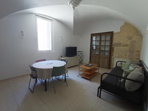 a living room with a table and chairs and a window at Dans maison de maître, appartement indépendant. in Montfrin