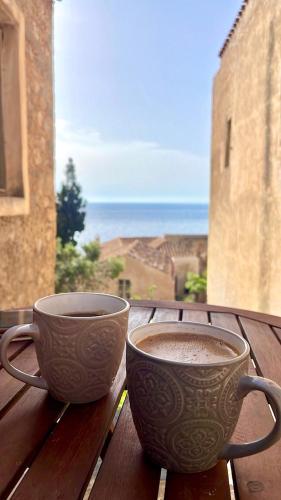 two cups of coffee sitting on top of a wooden table at Ritsos Family Apartment in Monemvasia