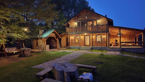 a large wooden house with a picnic table in the yard at Cabana Liliana Valea Doftanei in Trăisteni