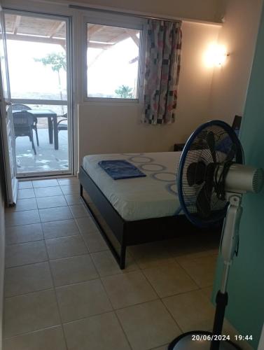 a room with a bed with a fan and a window at House on the wave relax in Koroni