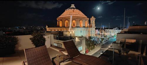 a view of a building at night with two chairs at Cinematique in Mosta
