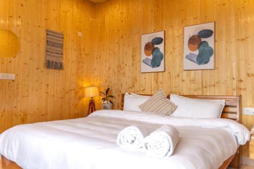 a bedroom with two beds with wooden walls at Ila by Aaryam, Kanatal in Chamba