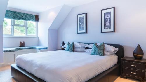 a bedroom with a large white bed with blue pillows at Superb 4BD Stay in Wyton and Houghton Village in Wyton