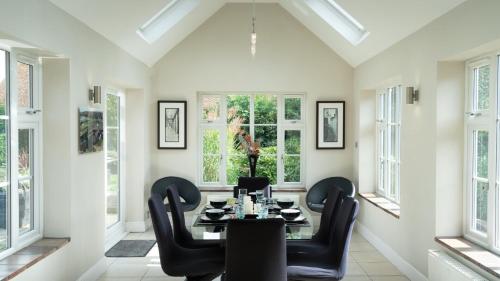 a dining room with a table and chairs and windows at Superb 4BD Stay in Wyton and Houghton Village in Wyton