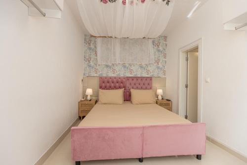 a bedroom with a pink bed and a window at O Quintal Guesthouse in Carvoeiro