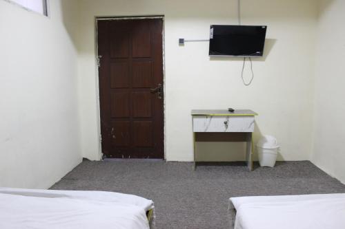 a room with a door and a desk and a television at Clock Tower Hotel in Shahr-e Now