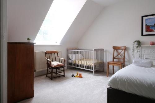 a bedroom with a bed and two chairs and a crib at Fantastic 2BD Victorian Apt - 4 adults & 1 child in Lewes