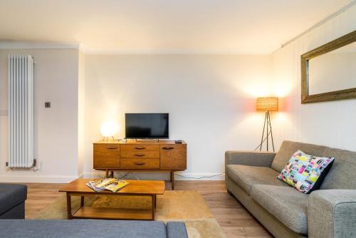 a living room with a couch and a tv at NEW Cosy 1BD Flat close to Kew Gardens Richmond in London