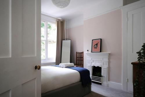 a white bedroom with a bed and a fireplace at Fantastic 2BD Victorian Apt - 4 adults & 1 child in Lewes