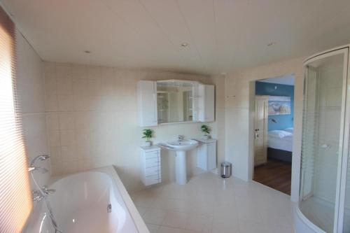 ein weißes Badezimmer mit Badewanne und Waschbecken in der Unterkunft Fijne vakantiehuizen 50 mtr van het strand in Egmond aan Zee
