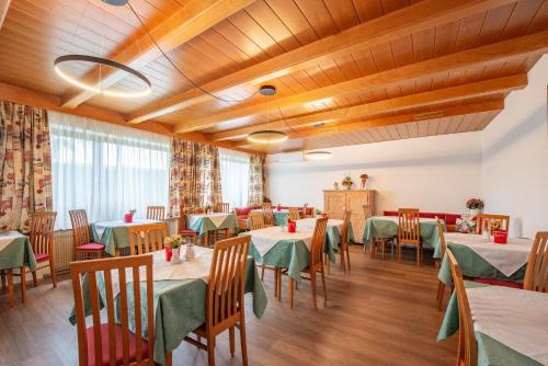 a restaurant with green tables and chairs and wooden ceilings at Pension Latemar in Caldaro
