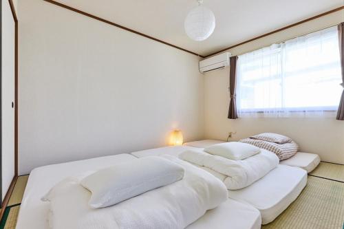 three beds in a room with a window at Fuji yamamiya 201 in Kofu