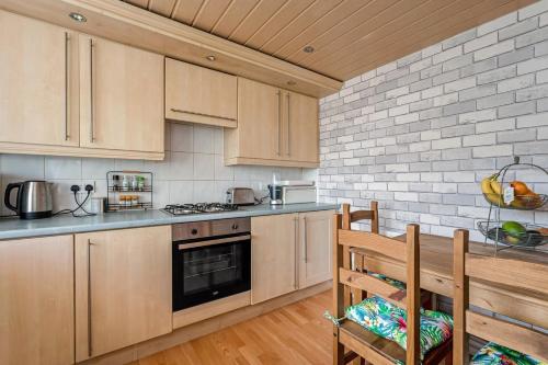 a kitchen with wooden cabinets and a brick wall at Centrally Situated 1 Bedroom House in Cumbernauld in Cumbernauld