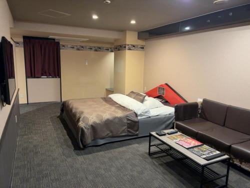 a bedroom with a bed and a couch and a table at ウォーターゲート蟹江 レジャーホテル in Kanie