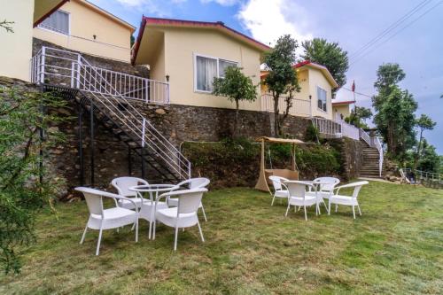 a group of tables and chairs in front of a house at Ila by Aaryam, Kanatal in Chamba