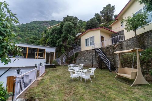 a patio with tables and chairs in front of a building at Ila by Aaryam, Kanatal in Chamba