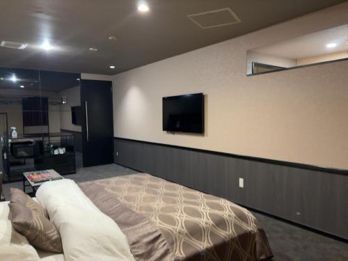 a bedroom with a bed and a flat screen tv on the wall at ウォーターゲート蟹江 レジャーホテル in Kanie