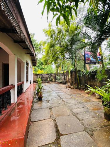 a stone walkway next to a building with trees at Sigiriya Sweet Home Guest House in Inamaluwa