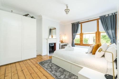 a white bedroom with a large bed and a fireplace at Beautiful 3BD Home Forest Hill South London in London