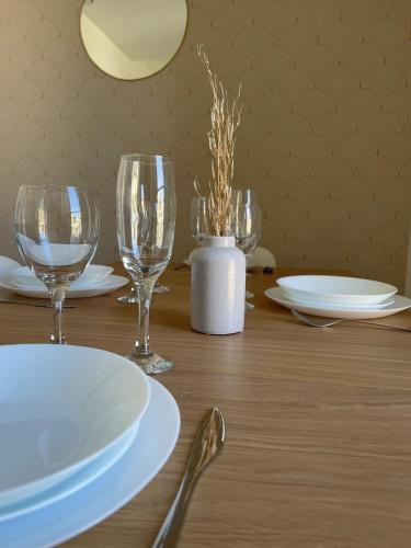 a wooden table with wine glasses and plates on it at La maison du Manoir 1900 in La Ferté-Gaucher