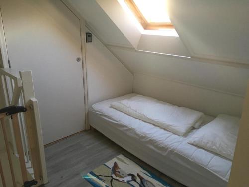 Cette petite chambre comprend un lit et une lucarne. dans l'établissement Heerlijke vakantiehuisjes in Egmond, à Egmond aan Zee
