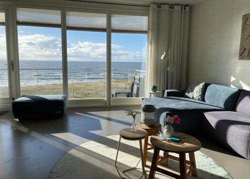 a living room with a blue couch and a view of the ocean at Boulevard Suite Strandloper in Egmond aan Zee