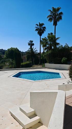 une piscine avec des palmiers en arrière-plan dans l'établissement Jolie Maisonnette vençoise, à Vence
