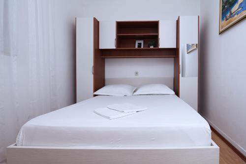 a bedroom with a white bed with a wooden headboard at Apartments Villa Flamingo in Makarska