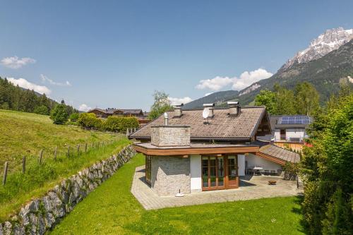 a house in a field with mountains in the background at Chalet Steinberg in Leogang